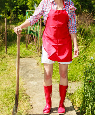 Middle age female with gardening tools outdoors. Woman standing with shovel in her backyardの写真素材