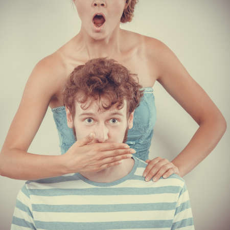 Emotional facial expression wide eyed couple, woman an man looking surprised, girl covering mouth her boyfriendの写真素材