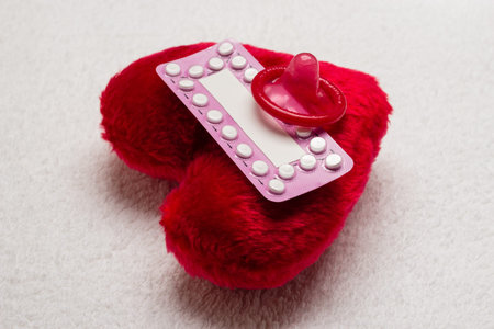 Medicine contraception love and birth control. Oral contraceptive pills condom on red heart shaped...