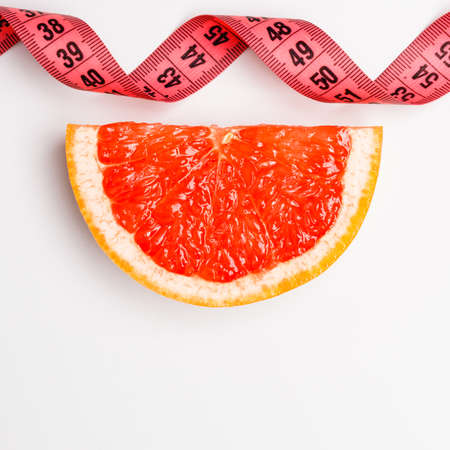 Diet healthy eating and slim body concept. Closeup red measuring tape centimeter and grapefruit copy space text areaの写真素材