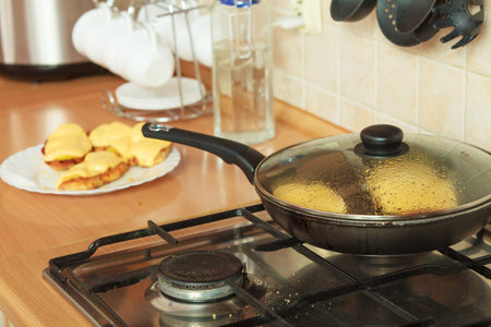 Frying breaded chicken cutlet with pineapples and cheese on fry pan. Making dinner meal.