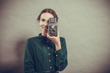 Woman retro style long dark gown taking picture with old camera, vintage photoの写真素材