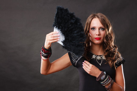 Portrait of beautiful brunette woman with black feather fan in hand