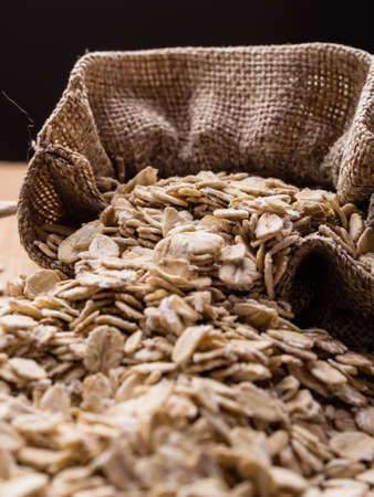 Dieting. Oat cereal in burlap sack on wooden surface. Healthy food for lowering cholesterol, protect heart.の写真素材