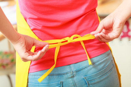 Closeup of woman tying apron up. Girl person cooking.