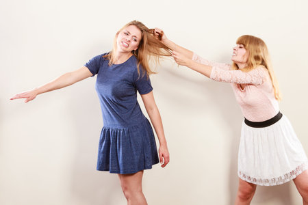 Aggressive mad women fighting each other pulling hair. Two young girls struggling win catfight....