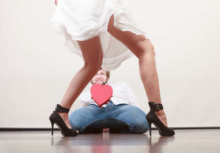 Man guy holding heart shaped present gift box for hot sexy woman girl in high heels. Valentine day love concept.の写真素材