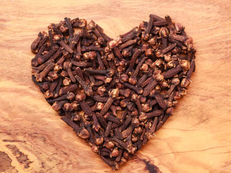 Heart form made from spice cloves on wooden backgroundの写真素材
