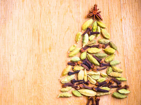 Christmas tree made from spices anise star cardamon pods and cloves on wooden backgroundの写真素材