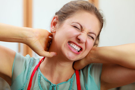 Overworked mature woman suffering from neck pain. Stressed female in kitchen.