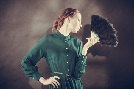Vintage woman retro style with black feather fan on dark