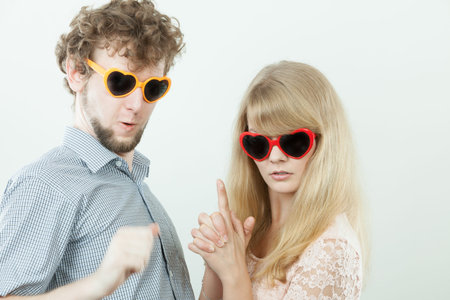 Happy young couple in heart shaped glasses. Smiling friends woman and man in studio.