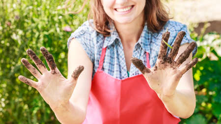 mature funny woman gardener wearing apron working in garden showing dirty handsの写真素材