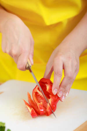 Healthy eating, vegetarian food, cooking, dieting and people concept. Woman in kitchen at home preparing fresh salad slicing vegetable red pepper closeupの写真素材