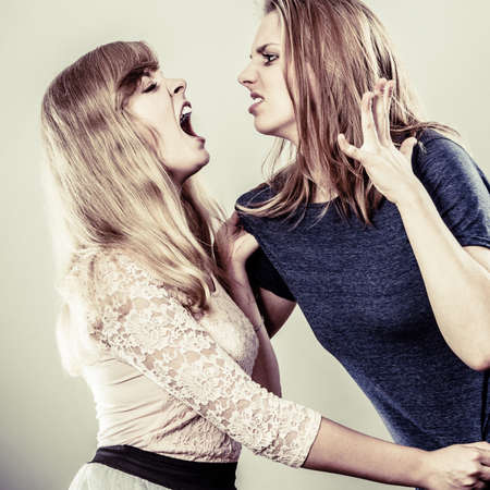 Aggressive mad women fighting each other pulling hair. Two young girls struggling win catfight. Violence.の写真素材