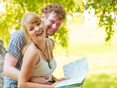 Man and woman tourists backpackers reading map on trip while resting.  Young couple hikers searching looking for direction guide. Backpacking summer vacation travel.の写真素材