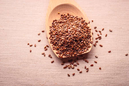 Healthy food for preventing heart diseases and overweight. Flax seeds linseed on wooden spoon burlap backgroundの写真素材