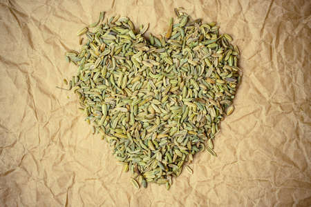 Dried fennel dill seeds heart shaped on paper surfaceの写真素材