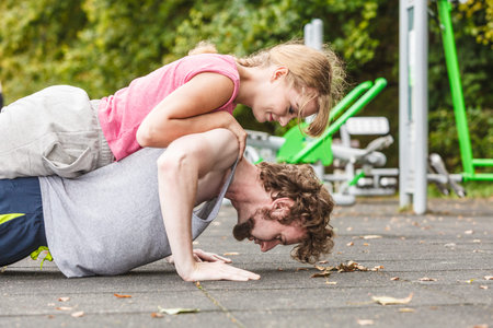 Active young man and woman exercising doing push ups. Muscular strong guy and girl in training suit...