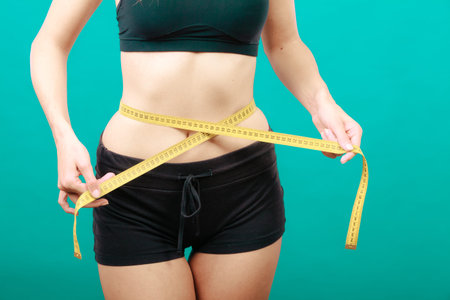 Weight loss, slim body, healthy lifestyle concept. Fit fitness girl measuring her waistline with...