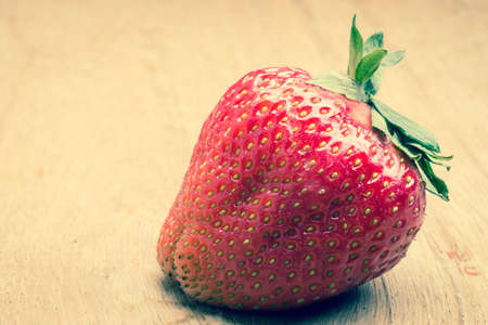 Healthy nutrition diet. Red fresh single strawberry fruit on wooden table boardの写真素材