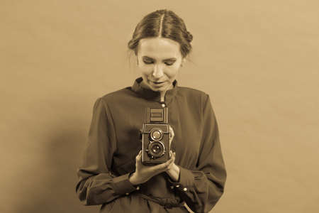 Woman retro style long dark gown taking picture with old camera, vintage photoの写真素材