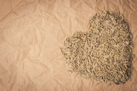Dried fennel dill seeds heart shaped on paper surface with copy spaceの写真素材