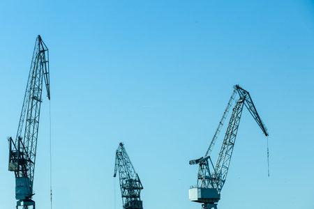 Business and commerce. Heavy load dockside cranes in port, cargo container yard. Industrial scene