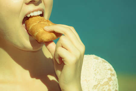 Closeup of woman eating croissant meal food outdoor. Girl having breakfast. Summer pleasure.の写真素材