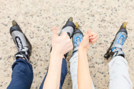 People friends with roller skates giving thumb up gesture. Woman and man relaxing outdoor.の写真素材