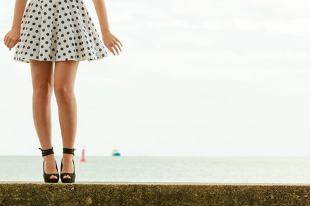 young beautiful woman retro styling wearing polka dot dress hihg heels outdoorの写真素材
