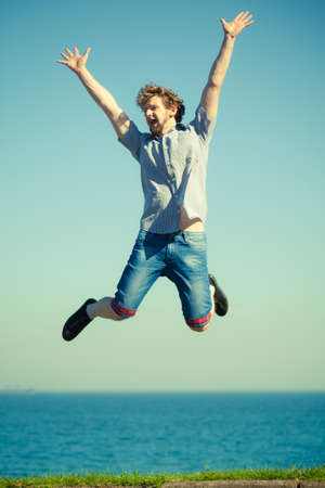 Carefree young man jumping by sea ocean water. Happy guy having fun. Summer happiness and freedom.の写真素材
