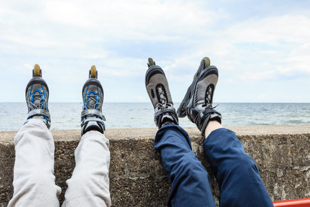 Closeup of people friends with roller skates. Woman and man relaxing outdoor.