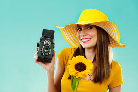 summer woman wearing yellow dress and hat with sunflower and old vintage camera in hand on vivid...