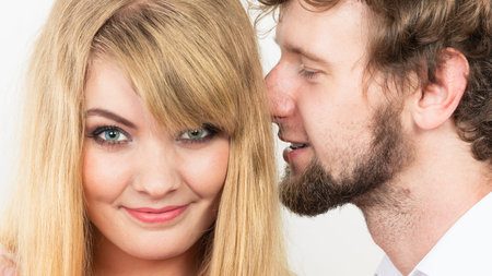 Loving couple with candy bunch bouquet flowers. Man whispering to woman ear sharing secret. Love and...