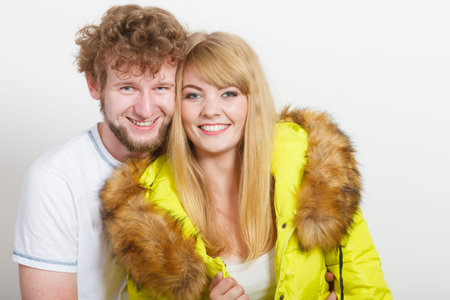 Happy joyful couple posing in studio. Young woman in warm lime jacket and man in white shirt. Winter autumn fall fashion.の写真素材