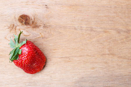 Red fresh single strawberry fruit on wooden table board copy space text areaの写真素材