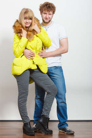 Happy joyful couple posing in studio. Young woman in warm lime jacket and man in white shirt. Winter autumn fall fashion.の写真素材