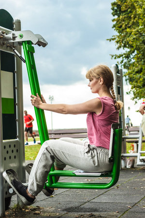 Active young woman exercising on leg press machine. Strong girl in training suit working out at...