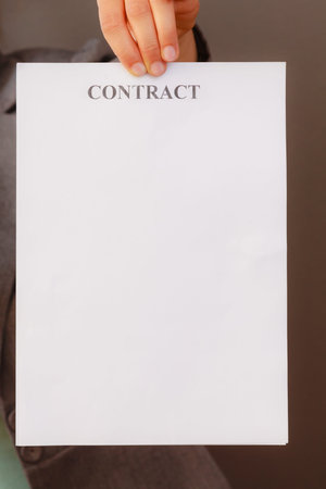 Contracts and agreements concept. Woman hand holding showing contract. Close up of palm with...