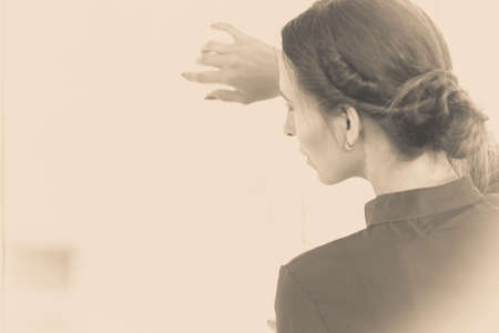 People and solitude concept. Alone woman looking through window waiting side view indoorの写真素材