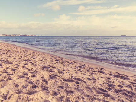 View of blue cloudy sky at sea or ocean water with footprints at sandy beach.の写真素材