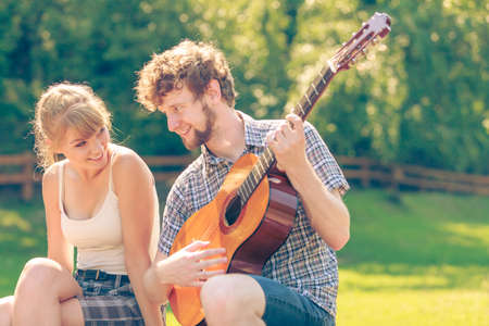 Adventure, tourism, enjoying summer time together - young couple tourists having fun playing guitar in campingの写真素材
