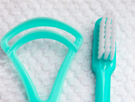 Oral hygiene health concept. Closeup dental tools green toothbrush and tongue cleaner on white towel
