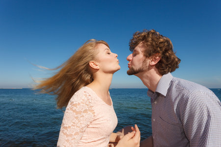 Happiness dating concept. Couple in love blonde woman handsome bearded man enjoy romantic date kissing, outdoor wide angle viewの写真素材