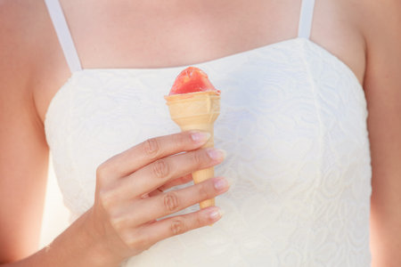 Summer holidays and happiness concept. Closeup young woman holding ice cream cone in hand