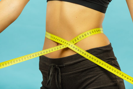 Weight loss, slim body, healthy lifestyle concept. Fit fitness girl measuring her waistline with...