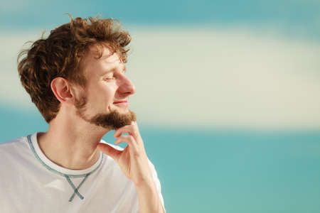 Man guy with closed eyes relaxing enjoying summer sunny day outdoor breating deep fresh air. Vacation holiday.の写真素材