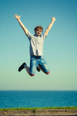 Carefree young man jumping by sea ocean water. Happy guy having fun. Summer happiness and freedom.の写真素材