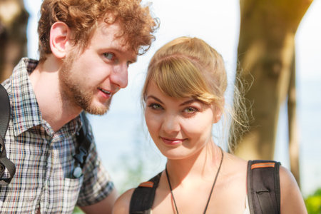 Two young people tourists hiking outdoor. Backpackers couple on summer vacation trip journey. Man...